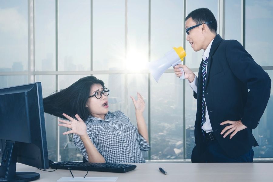 A shocked female employee being shouted by her boss