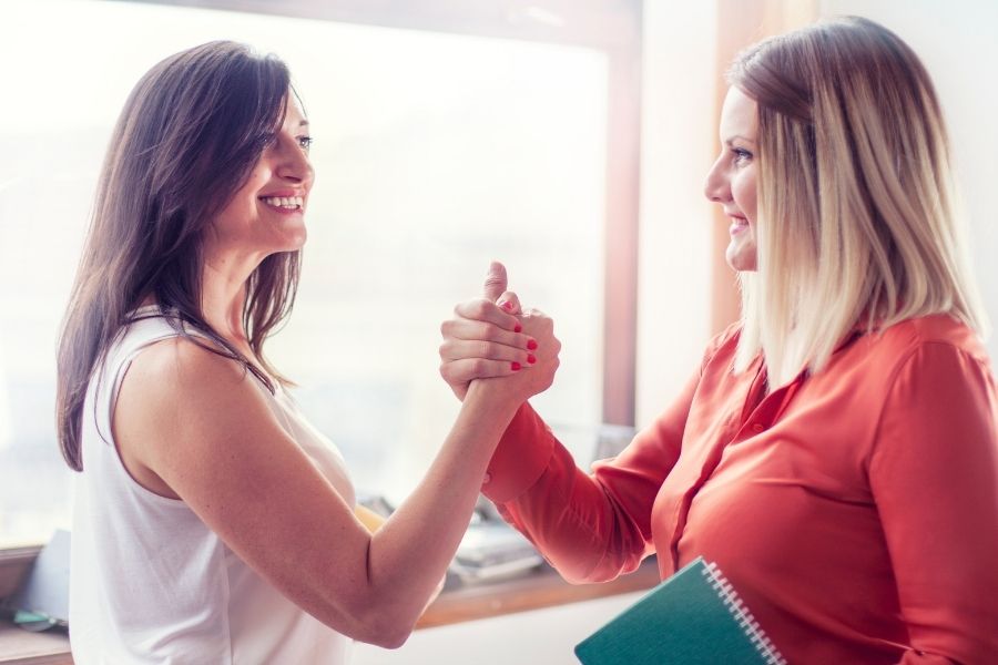 two females holding hands as sign of unity and support