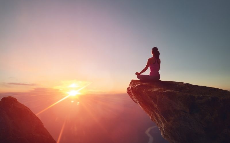 A lady is doing Meditation in sunset