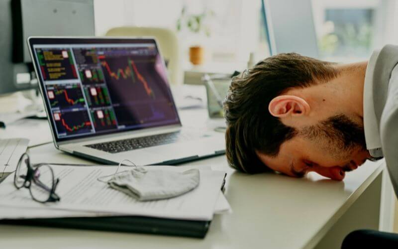 Disappointed young manager knocks his head on the table after analyzing the company's financial budget, failure in business during pregnancy.