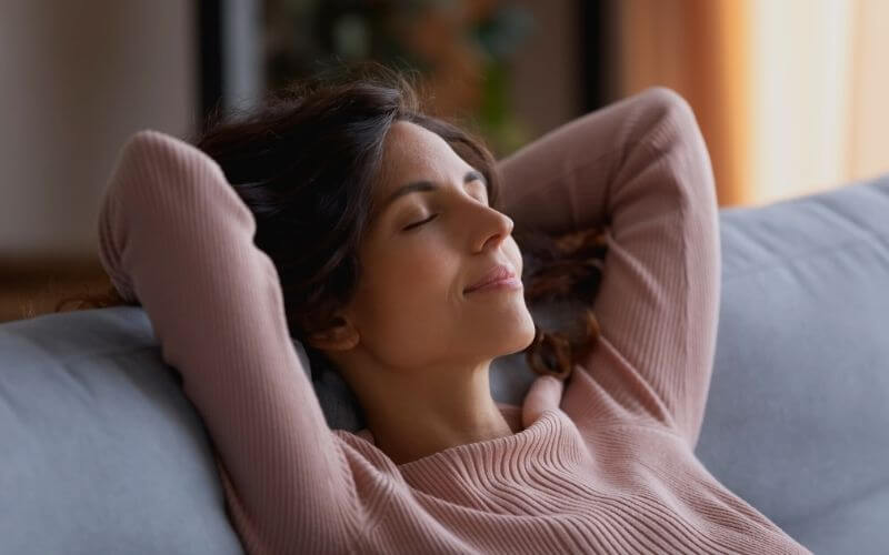 Smiling serene Hispanic woman close her eyes put hands behind head breath fresh 