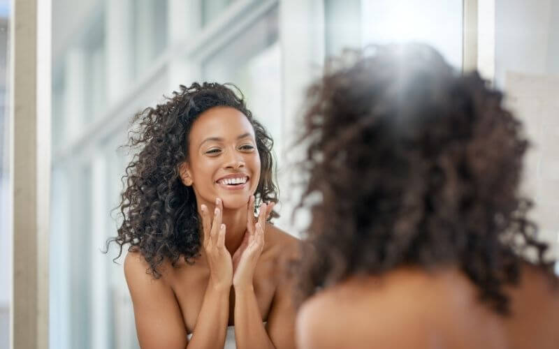 Shot of an attractive young woman admiring her face in the bathroom mirror