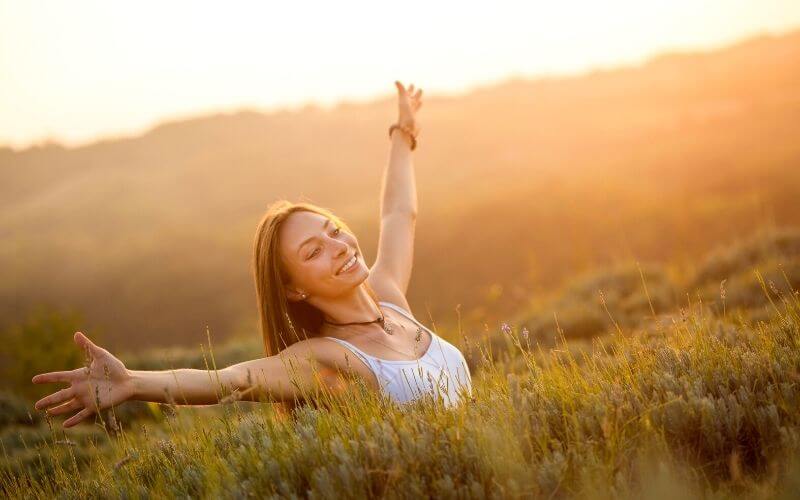 Smiling young woman in nature, feeling happy. 