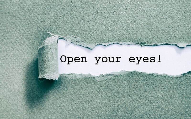 Open your eyes written under torn paper.