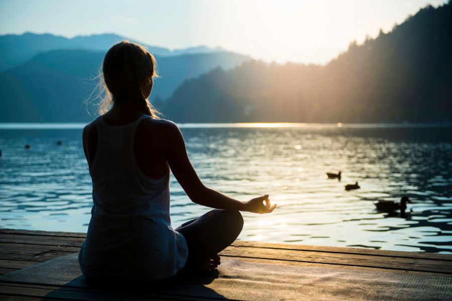 A lady mediating beside a lake