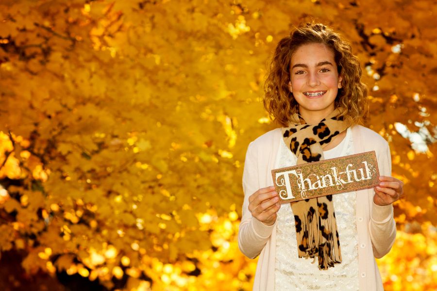 A young teenager holding a sign saying thankful