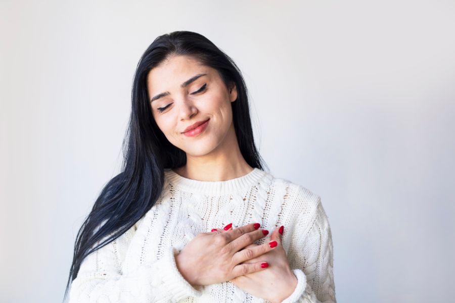 A smiling woman hugging herself