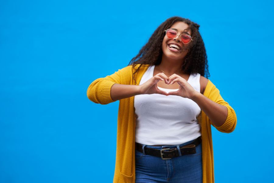 An attractive young woman showing love sign in a blue background