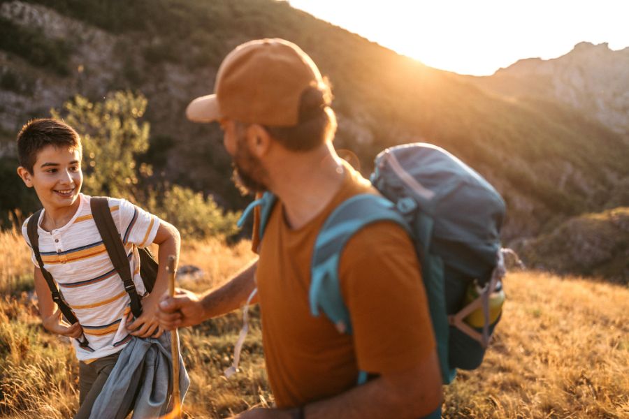 cheerful teenage boy with his dad in mountains