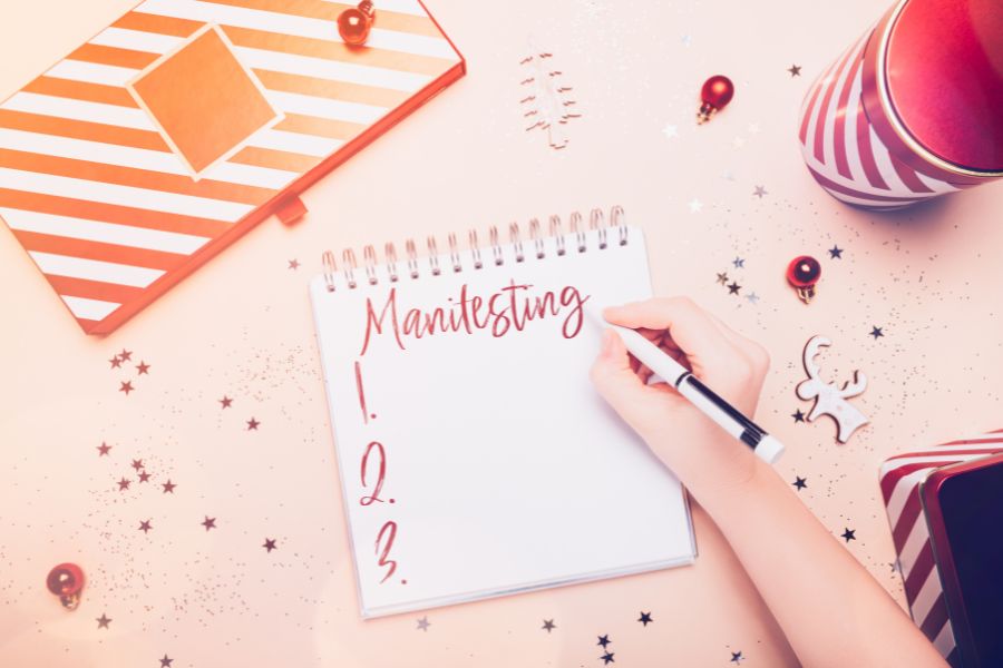 A woman writing Manifesting on a paper