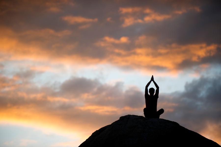 A man doing yoga during sunset
