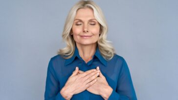 Happy mindful middle aged woman holding hands on chest representing empath quotes