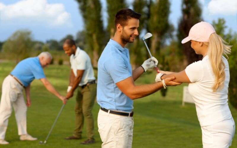 The female golfer learns golf, the male coach helps
