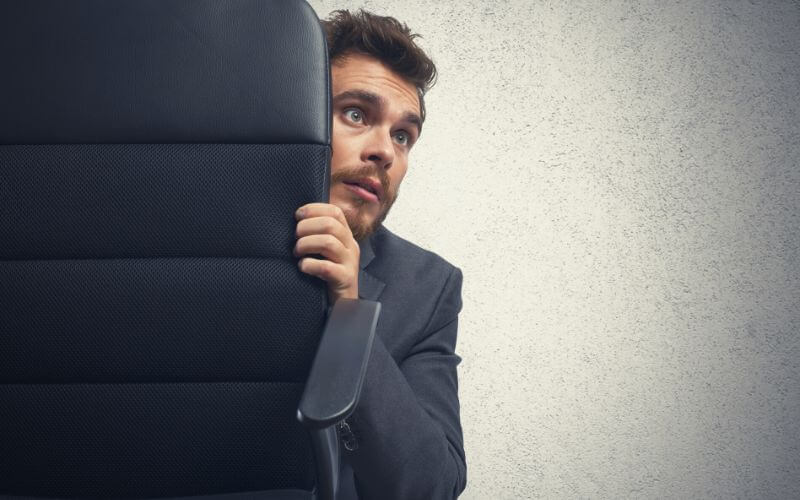 The concept of fear of a businessman behind a chair