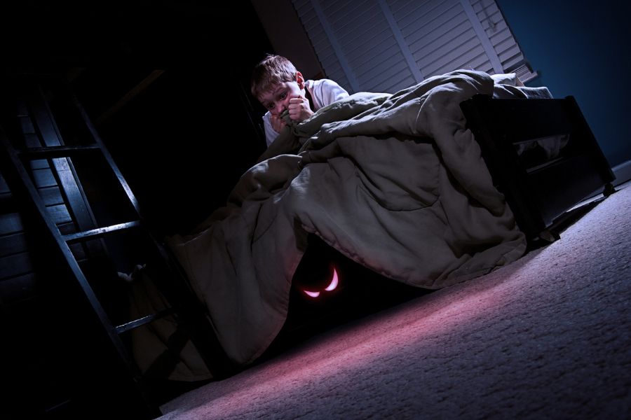 A frightened child and a monster under the bed showing Teraphobia